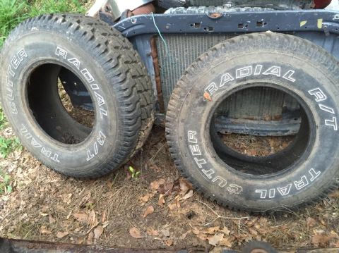 1996 Ford Bronco - Two off-road tires with white lettering are displayed on the ground in front of a radiator and vehicle frame. The tires read "CUTTER TRAIL…