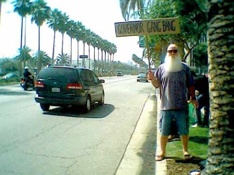 1988 Ford Bronco - A man with a long white beard stands on a sidewalk next to a street with a minivan and a motorcycle.
