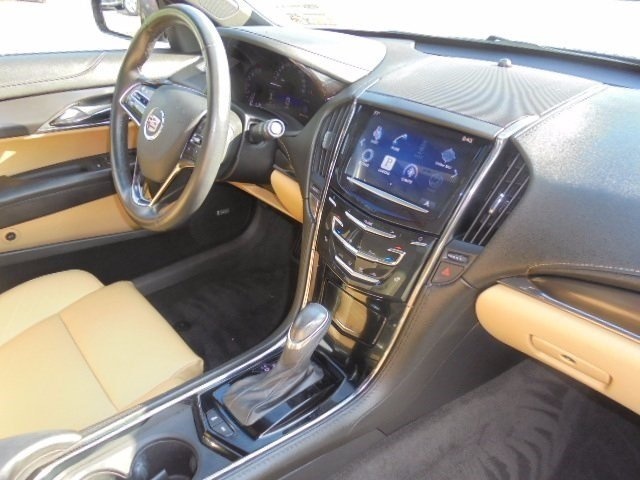Interior of a Cadillac sedan with tan seats, black dashboard, and touchscreen.