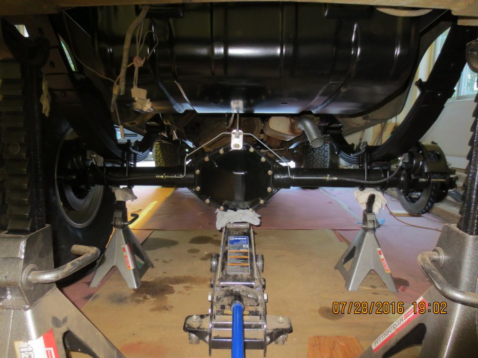 Underside view of a vehicle's rear axle assembly supported by jack stands.