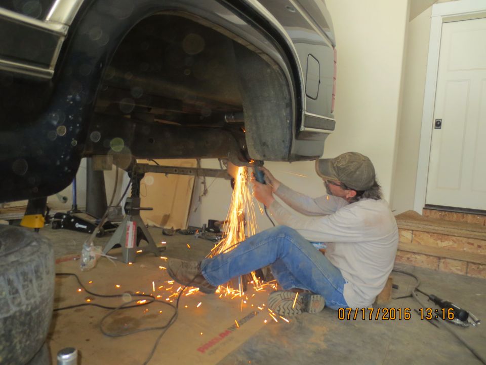 Person grinding under a dark SUV/truck, sparks flying.