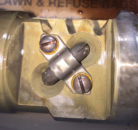 1978 Ford Bronco - A close-up view shows a metal component with a toothed edge, featuring a cross-shaped clamp secured by two screws. The component appears to…