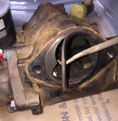1978 Ford Bronco - A close-up, rusty metal part, possibly a steering component, is shown with a tool inserted into a circular opening. The part appears to be…