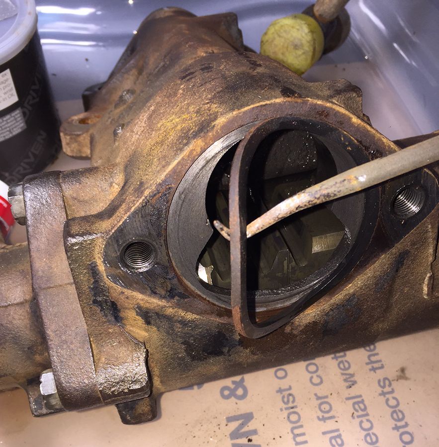 Close-up of a rusty metal part with a tool inserted, possibly from a 1978 Ford Bronco.