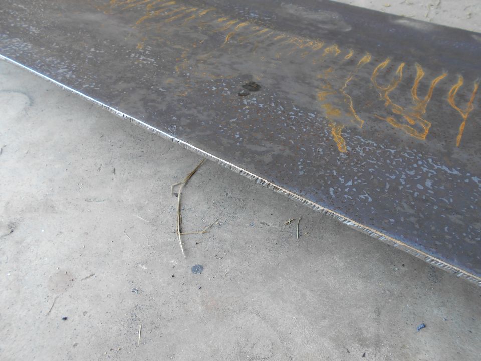 Close-up of a metal beam with rust marks on a concrete surface.