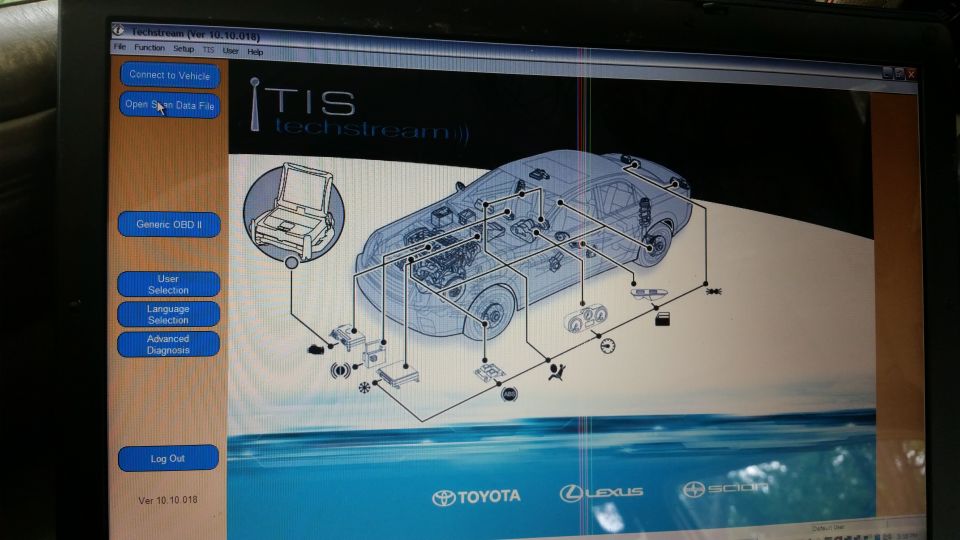 Laptop screen showing car diagnostic software with component diagram and menu options.