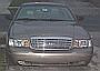 2003 Ford Crown Victoria - This is a front-facing photograph of a tan sedan, a prominent chrome grille and headlights.