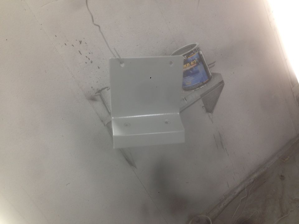 Gray metal bracket with holes next to a can of paint.