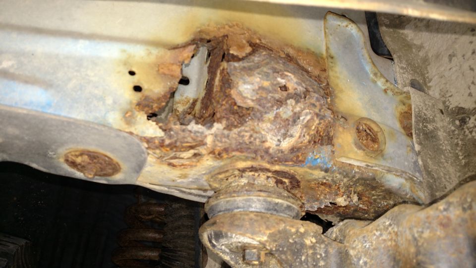 Severely rusted vehicle frame and suspension components, including a ball joint.