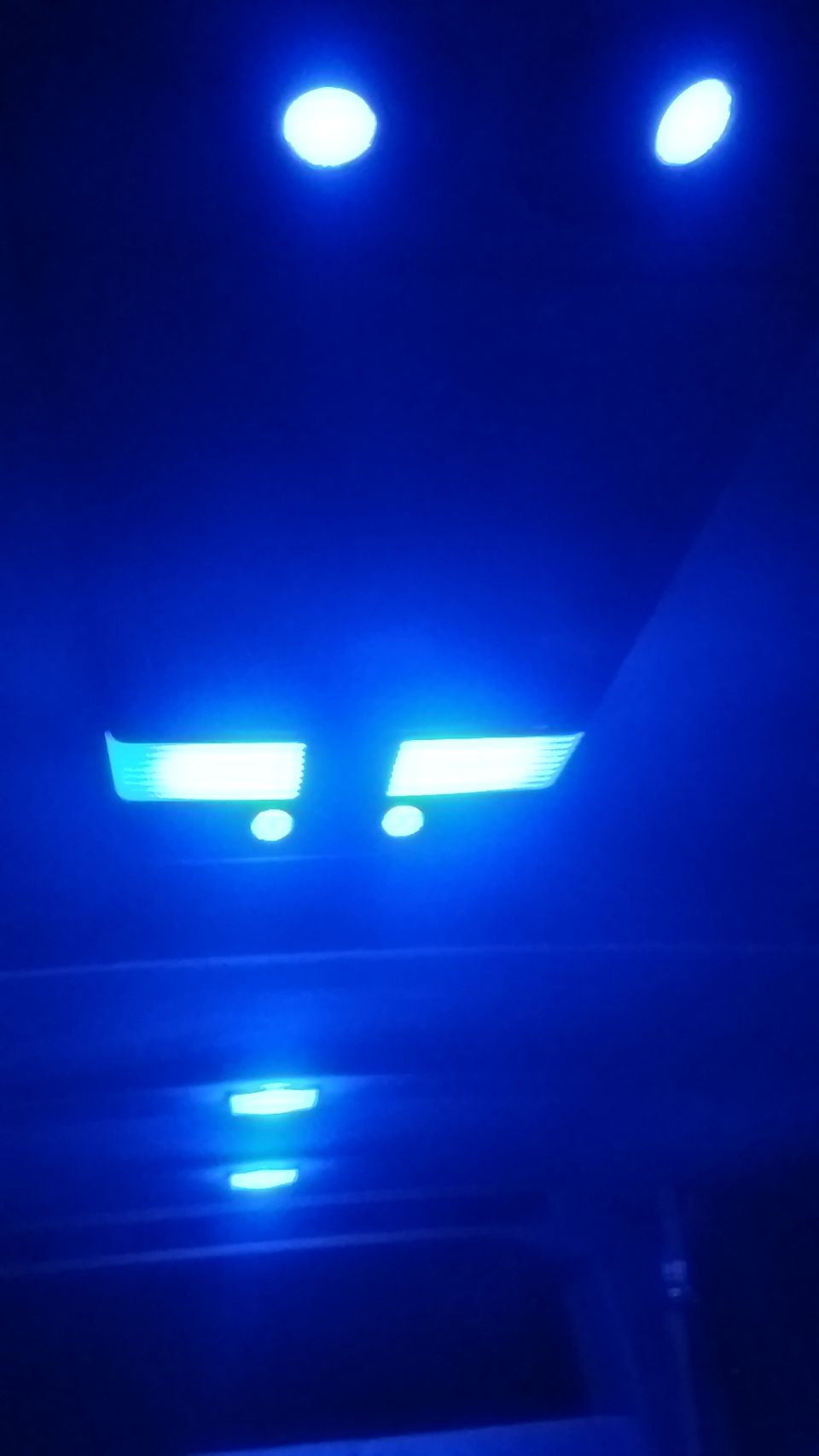 Interior ceiling of a vehicle with multiple blue LED lights, including two rectangular and two circular lights.