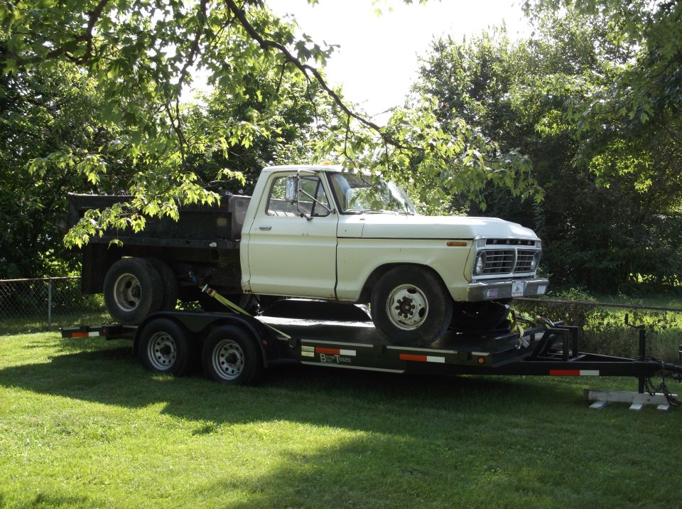 White 1974 Ford F-350 flatbed truck on a trailer.