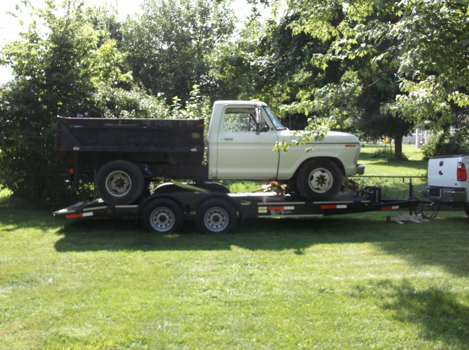 White 1970s Ford pickup truck on a trailer with another truck bed.