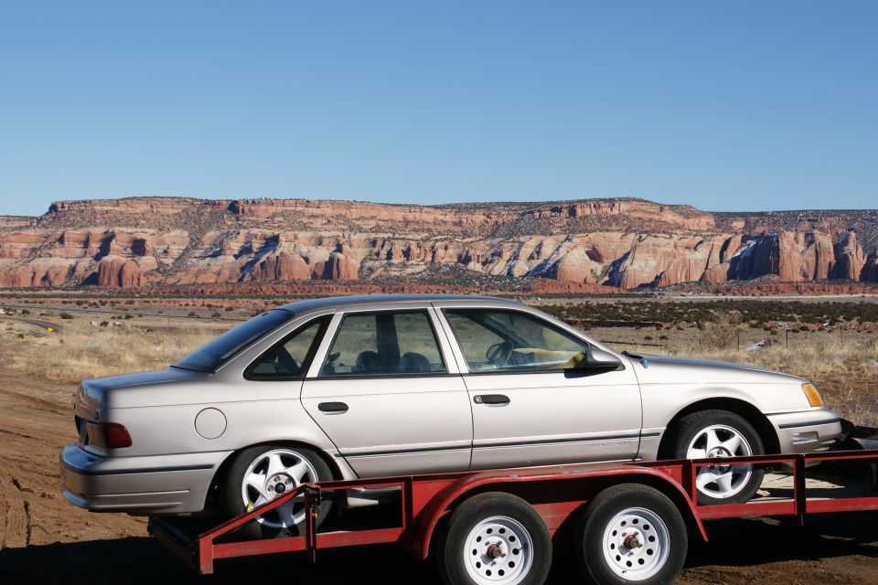 Silver sedan on a red trailer with red rock formations in the background.