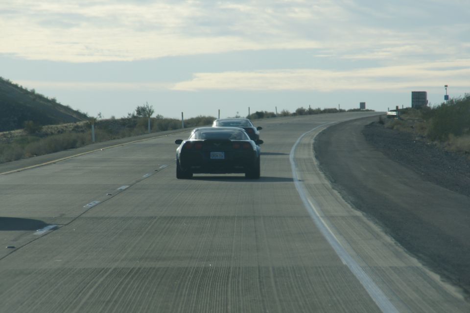 Two black Chevrolet Corvettes on a highway.