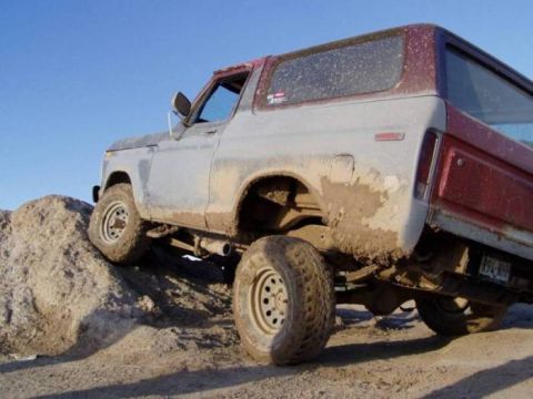 1978 Ford Bronco - This 1978 Ford Bronco is shown off-road, navigating a dirt hill with mud splattered on its body.