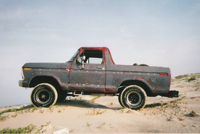 1978 Ford Bronco, gray with red accents, side view, on sandy terrain