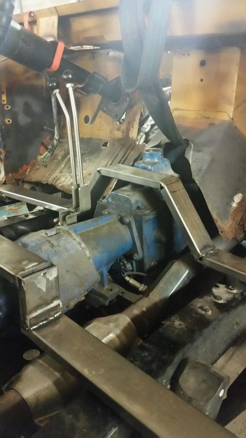 1979 Ford Bronco - Custom metal fabrication is underway in the engine bay of a vehicle, likely a Ford Bronco, with a blue transmission or transfer case visibl…