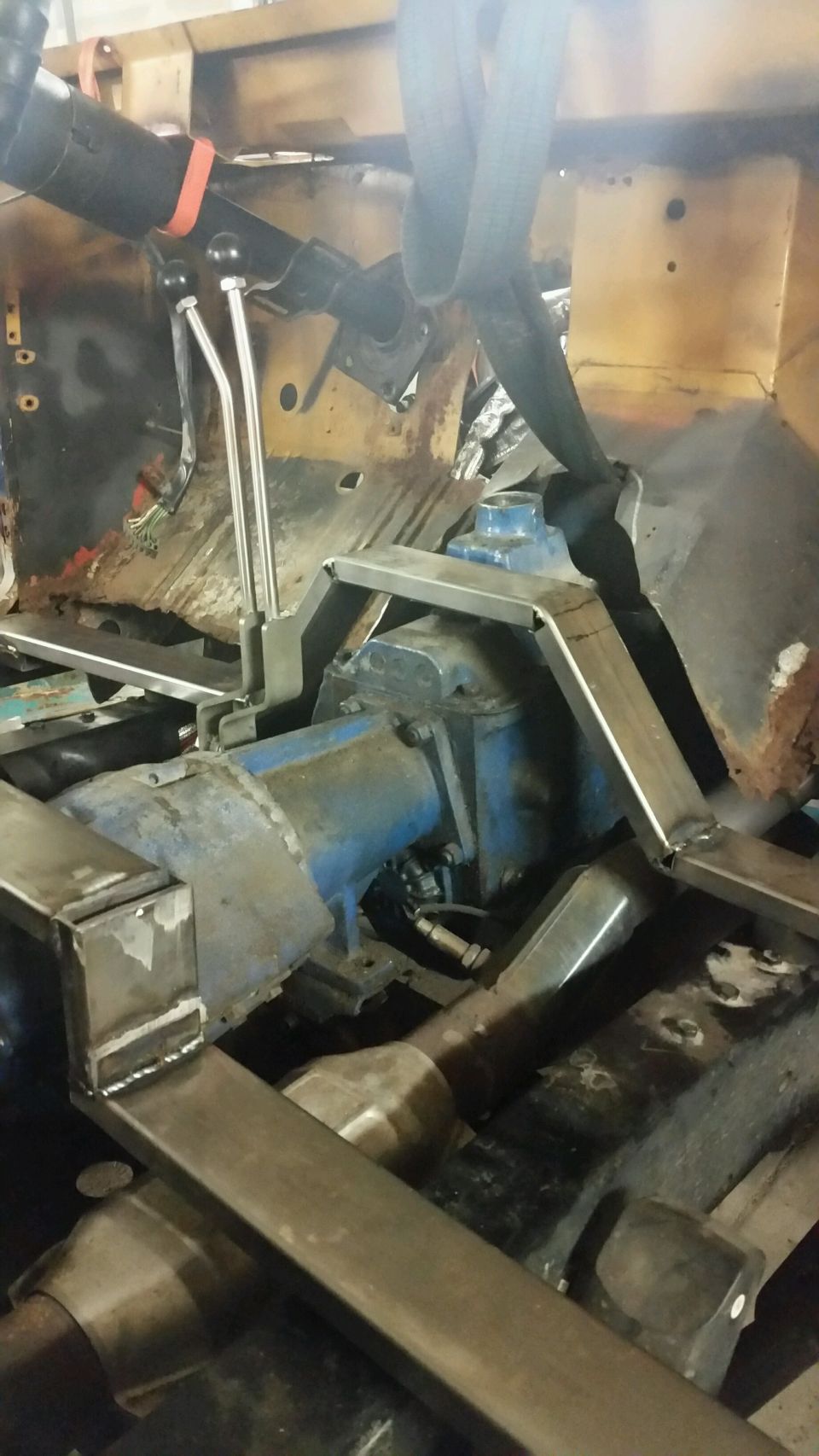 Close-up of custom metal brackets being welded in a vehicle engine bay.