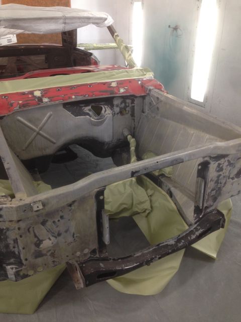1964 Ford Fairlane - The front end of a 1964 Ford Fairlane is visible, covered in masking and primer, inside a paint booth.