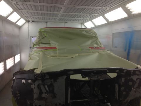 1964 Ford Fairlane - A truck cab, likely undergoing preparation for painting, is centered in a brightly lit paint booth.