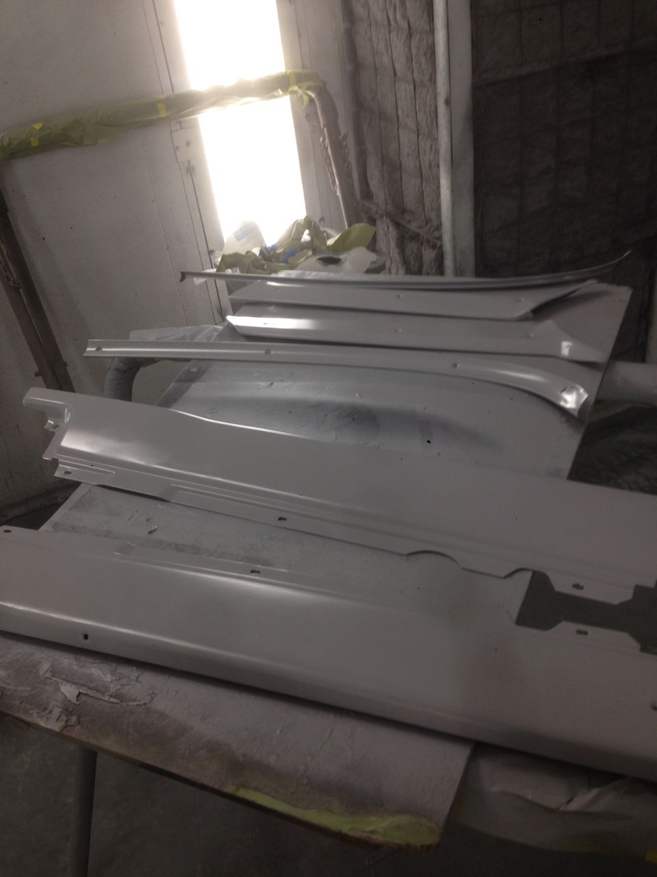 Shelves holding various car parts, possibly for a restoration project