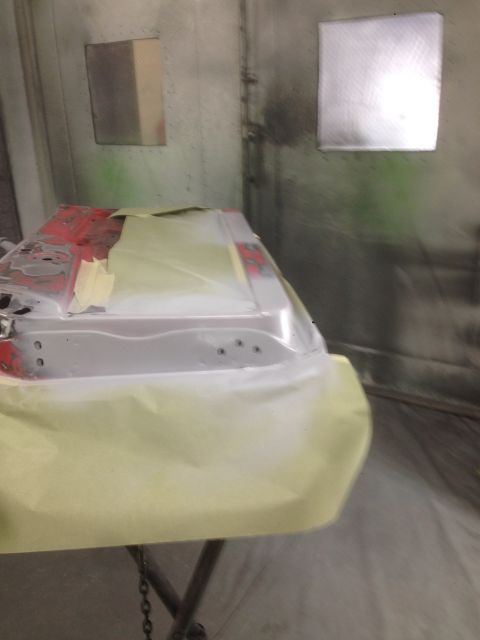 1964 Ford Fairlane - A car door is prepared for painting inside a booth, with masking paper covering most of the surface.