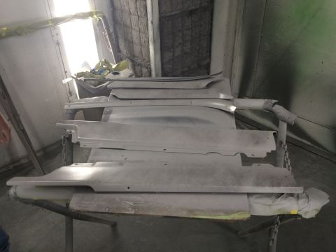 1964 Ford Fairlane - Several car body panels are stacked on a stand in a paint booth, awaiting refinishing.
