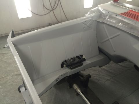 1964 Ford Fairlane - The bare metal chassis of a car is shown in a paint booth, ready for its new coat.