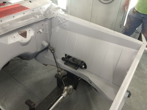 1964 Ford Fairlane - The engine bay of a car is being prepped for paint, showing the firewall and steering components.