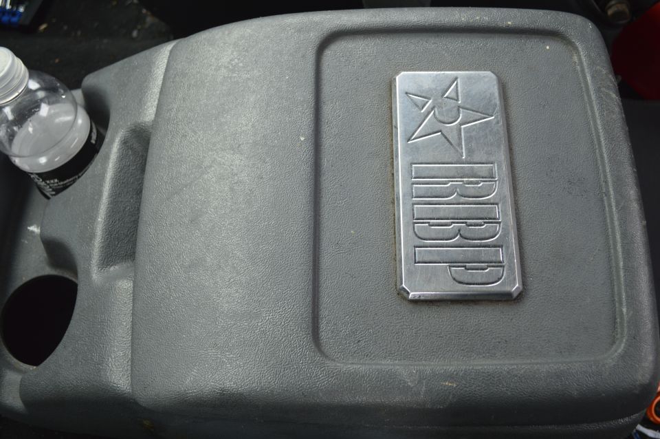 Gray center console with a metal RBP badge and a water bottle in a cup holder