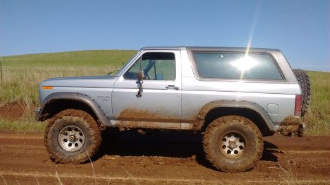 1985 Ford Bronco - This Ford Bronco is shown off-road, with mud splattered on its body and tires.