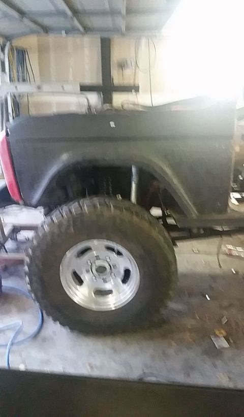 1979 Ford Bronco - The side profile of a dark Ford Bronco shows its distinctive body shape and a large off-road tire, indicating a model year prior to 1979.