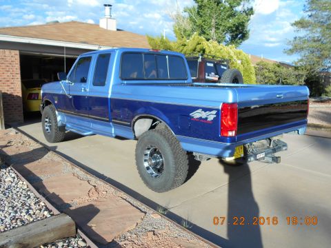 1996 Ford F-250 - A blue two-tone Ford F-250 pickup truck is parked in a driveway with a garage in the background.