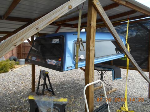 1996 Ford F-250 - A blue truck bed cap is suspended by straps for removal or installation.