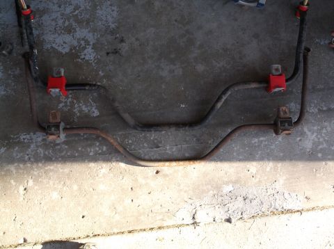 2001 Mercury Grand Marquis - Two sway bars, one with red bushings, are shown laid out on a concrete surface.