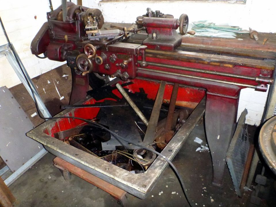 Red metal lathe with tools in a scrap bin