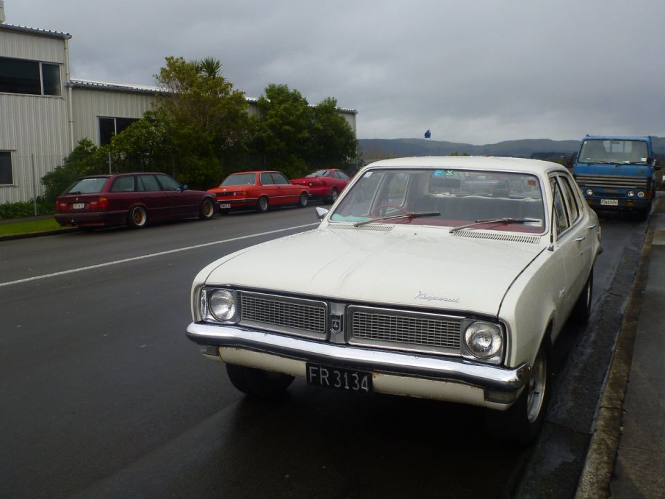 White sedan with chrome grille and FR 3134 license plate parked on a wet street