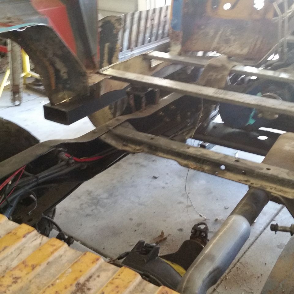 Undercarriage and frame of a vehicle undergoing repair, showing suspension and exhaust components