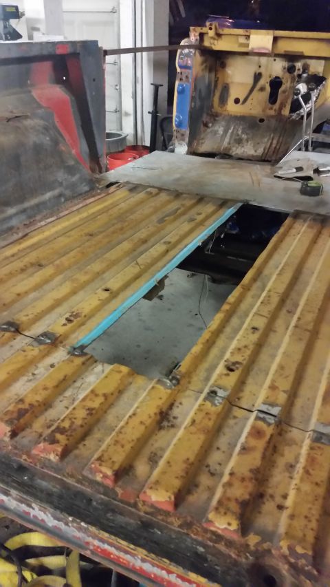 1979 Ford Bronco - The bed of a truck shows significant rust and a hole in the floor, exposing the undercarriage.