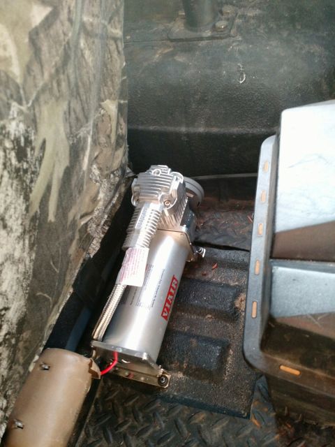 1992 Ford Bronco - A VIAIR air compressor is visible inside a vehicle, mounted on the floor near a seat.