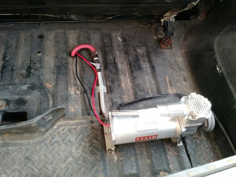 1992 Ford Bronco - A VIAIR air compressor is installed in the cargo area of a vehicle.