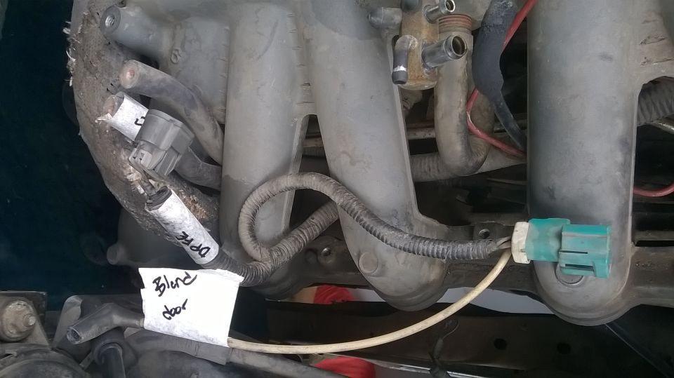 Engine intake manifold with sensors and wiring. Paper note says 'Blind door'