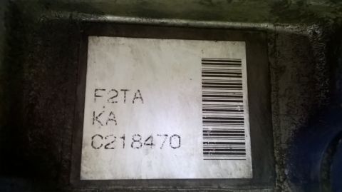 1996 Ford F-150 - A label with alphanumeric codes and a barcode is affixed to a dark, possibly engine-related component.