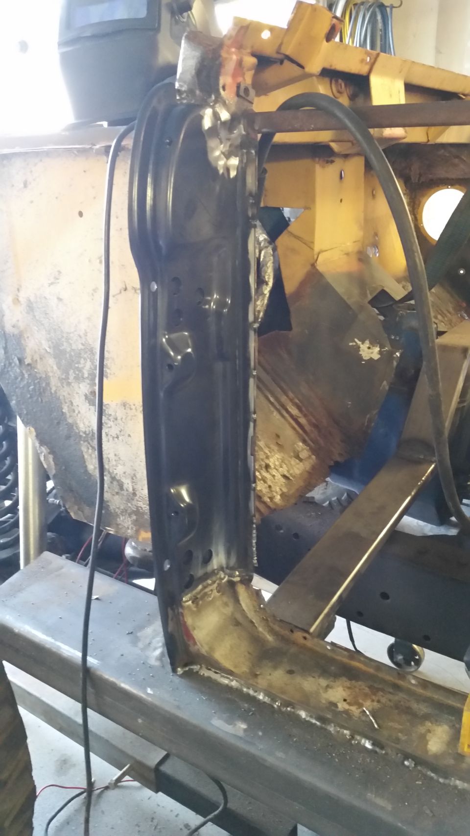 Vehicle body repair with fresh welds, yellow structural components in background