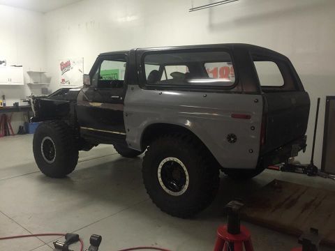 1979 Ford Bronco - A modified 1979 Ford Bronco is shown in a garage setting. The vehicle has large off-road tires and appears to be undergoing some bodywork o…