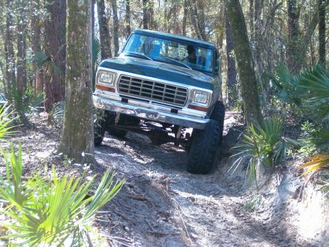 1991 Ford Bronco - Ford Bronco tackling rough terrain in a forest setting.