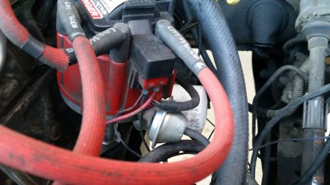 1981 Ford Bronco - A close-up view of a vehicle's ignition system, featuring red spark plug wires connected to a distributor cap. Text on the wires reads "LIV…