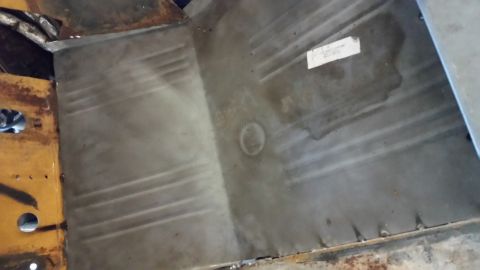 1979 Ford Bronco - The image shows the interior floor pan of a vintage vehicle, likely a truck or SUV, with visible metal stamping and some surface rust. A wh…