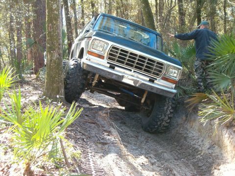 1991 Ford Bronco - This lifted Ford Bronco navigates a challenging off-road trail through a wooded area.