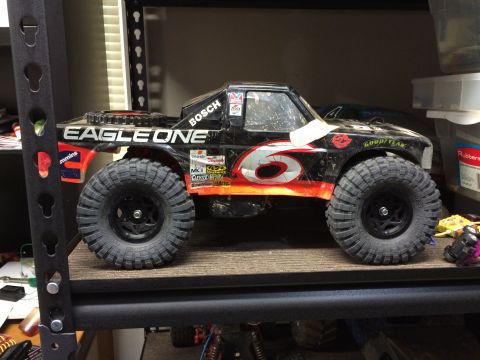 1989 Ford Bronco - A modified remote-controlled monster truck with "EAGLE ONE" and "BOSCH" text on the side sits on a shelf.